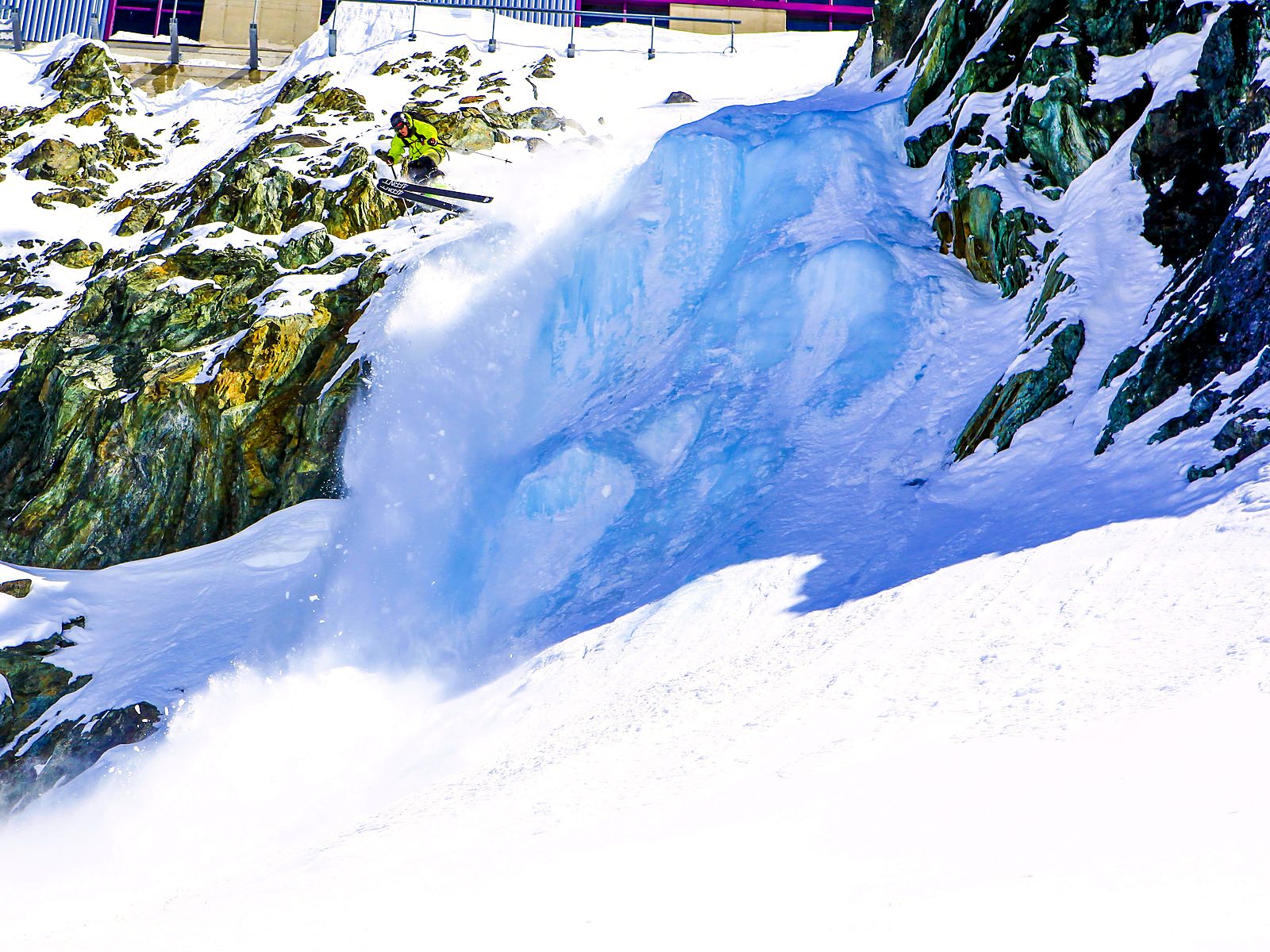 Freeride skier dropping beside a frozen waterfall in Saas-Fee