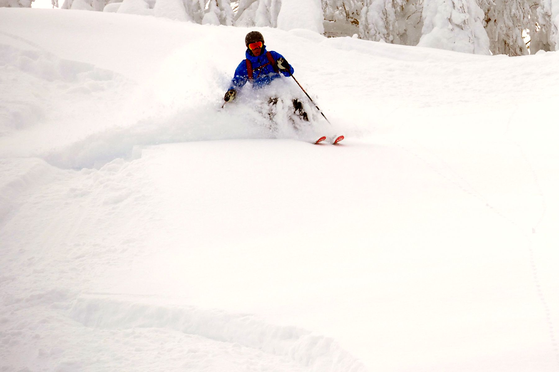 Powder skiing down a steep slope with snow spray